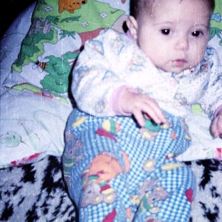Baby wearing Winnie the Pooh pajamas, lying on bed.