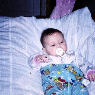Baby sleeping peacefully with pacifier in bed.