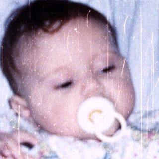 Baby sleeping peacefully with pacifier in bed.