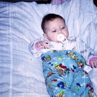 Baby sleeping peacefully with pacifier in bed.