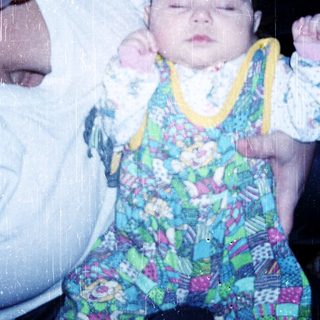 A person holding a sleeping baby in colorful pajamas.
