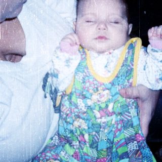A person holding a sleeping baby in colorful pajamas.
