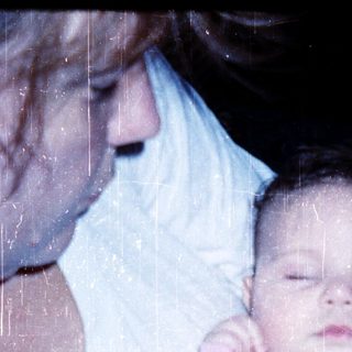 A person holding a sleeping baby in colorful pajamas.