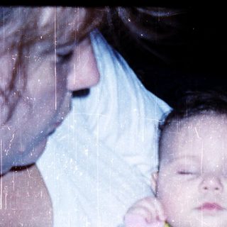 A person holding a sleeping baby in colorful pajamas.