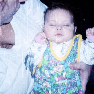 A person holding a sleeping baby in colorful pajamas.