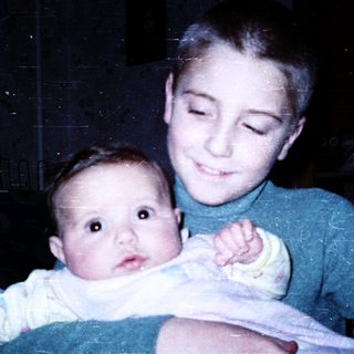 Young boy holding an infant indoors.