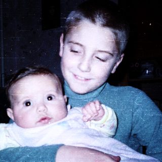 Young boy holding an infant indoors.