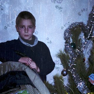 Christmas scene with boy and baby near decorated tree.