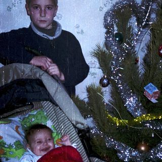Christmas scene with boy and baby near decorated tree.