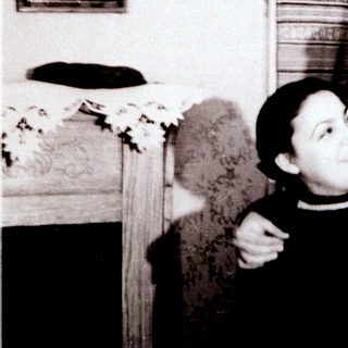 Two people posing affectionately indoors, mid-20th century.