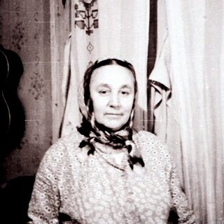 Old woman in traditional attire indoors.