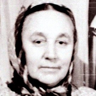 Old woman in traditional attire indoors.