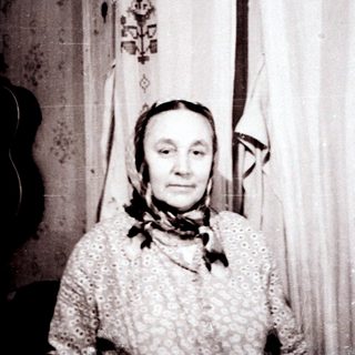 Old woman in traditional attire indoors.