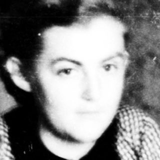 Young boy sitting indoors, mid-20th century.