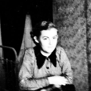 Young boy sitting indoors, mid-20th century.