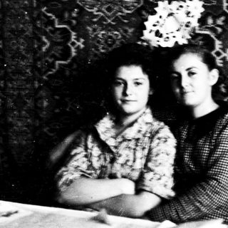 Two young women posing indoors, early 20th century.
