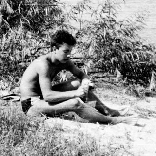 Two people sitting by a riverbank.