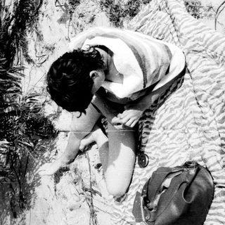 Person bending to examine or interact with water.