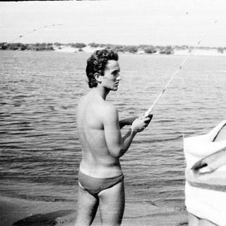 Two men fishing at a waterfront.