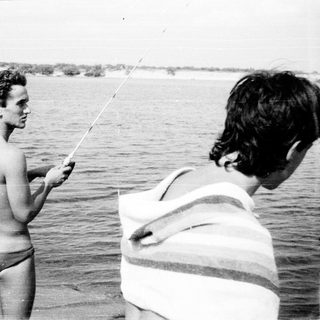 Two men fishing at a waterfront.