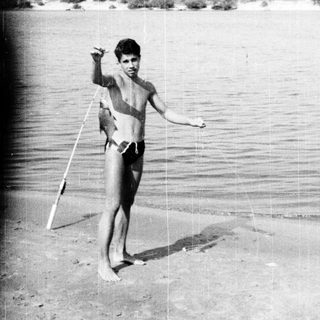Young boy holding surfboard near ocean.