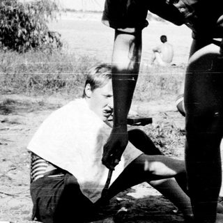 Two adults assisting a child in outdoor setting.