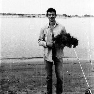 Man holding fishing net by water.
