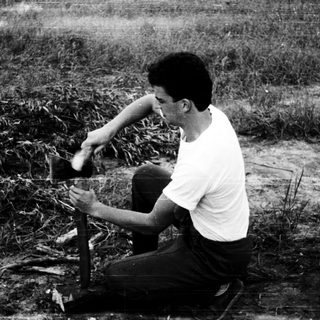 Man fishing with a rod in a grassy, outdoor area.