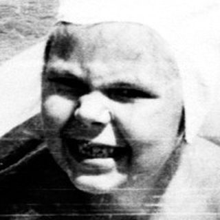Person wrapped in white sheet swimming in crowded water.
