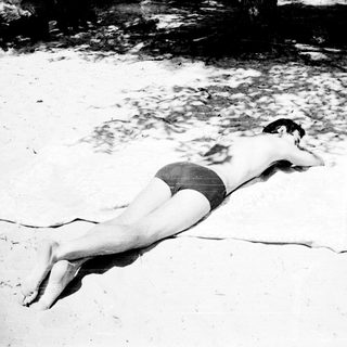 A person sunbathing on a sandy beach.
