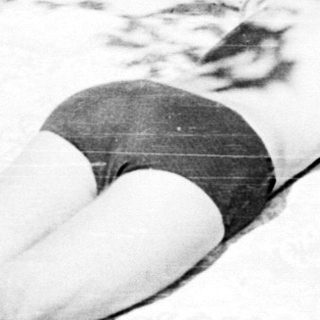A person sunbathing on a sandy beach.