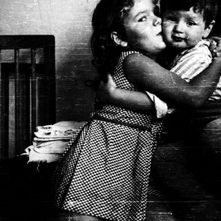 Two children hugging affectionately indoors.