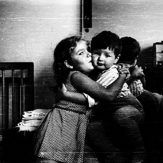 Two children hugging affectionately indoors.