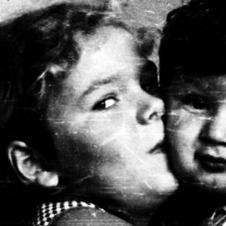 Two children hugging affectionately indoors.