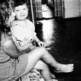 Young girl sitting on woman's lap indoors.