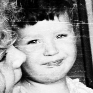 Young girl sitting on woman's lap indoors.