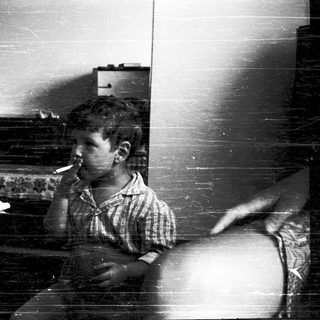 Young boy smoking cigarette indoors near window.