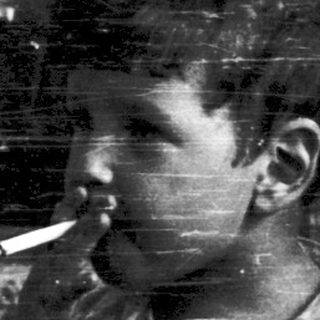 Young boy smoking cigarette indoors near window.