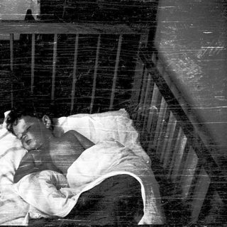 A person sleeping in a confined metal bed.