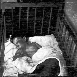 A person sleeping in a confined metal bed.