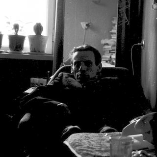 Man resting on bed near window with glass.