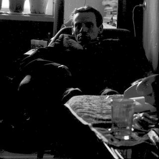 Man resting on bed near window with glass.