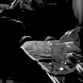 Man resting on bed near window with glass.