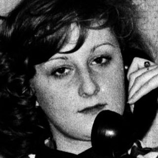 Woman in checkered dress talking on vintage phone.
