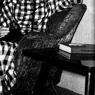 Woman in checkered dress talking on vintage phone.