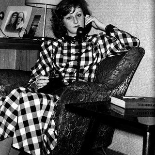 Woman in checkered dress talking on vintage phone.