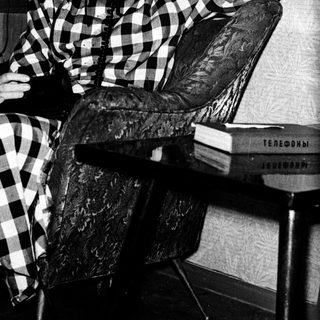 Woman in checkered shirt talking on vintage phone.