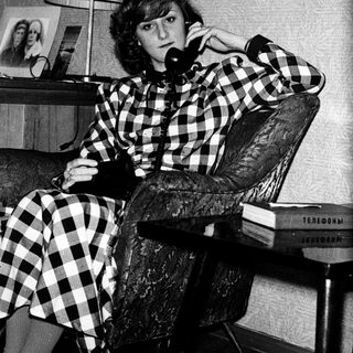 Woman in checkered shirt talking on vintage phone.