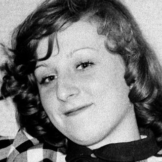 Young woman posing with cat in checkered shirt.
