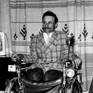 Man in wheelchair attached to motorcycle.